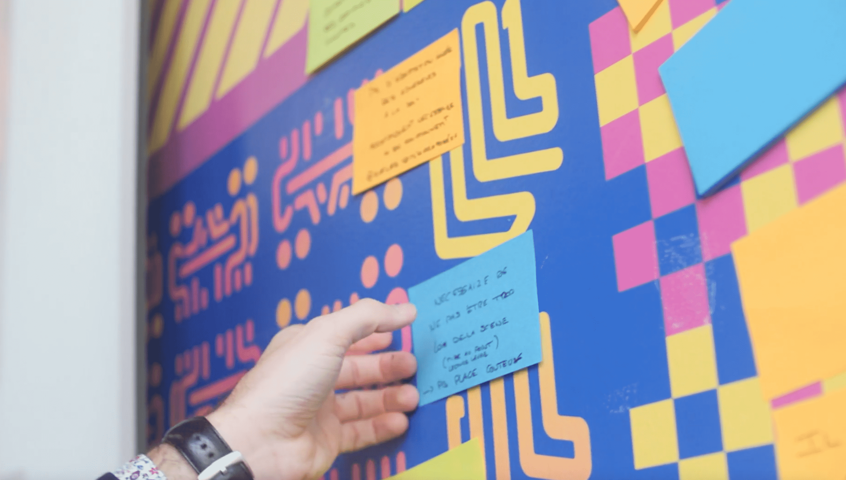 Une main qui dépose un post-it au mur