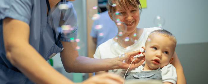 Enfant qui passe un test auditif dans les bras de sa mère