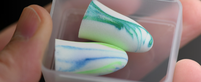 Une main qui tient une boîte avec une paire de bouchons d'oreille à l'intérieur