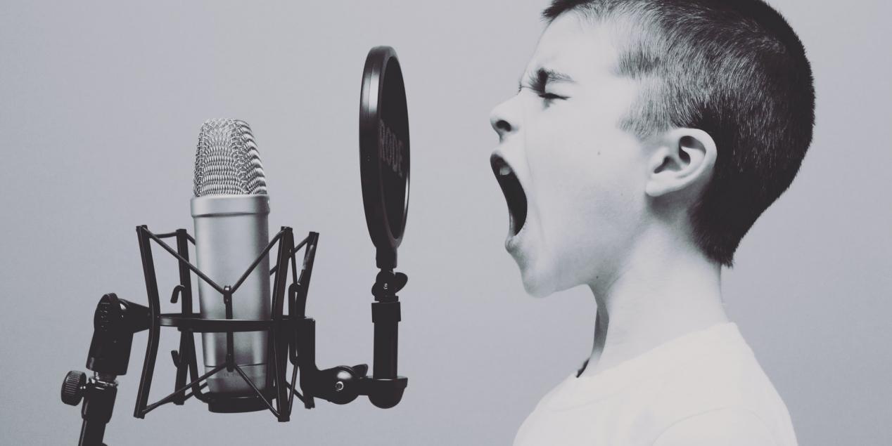 Un enfant élève sa voix dans un micro